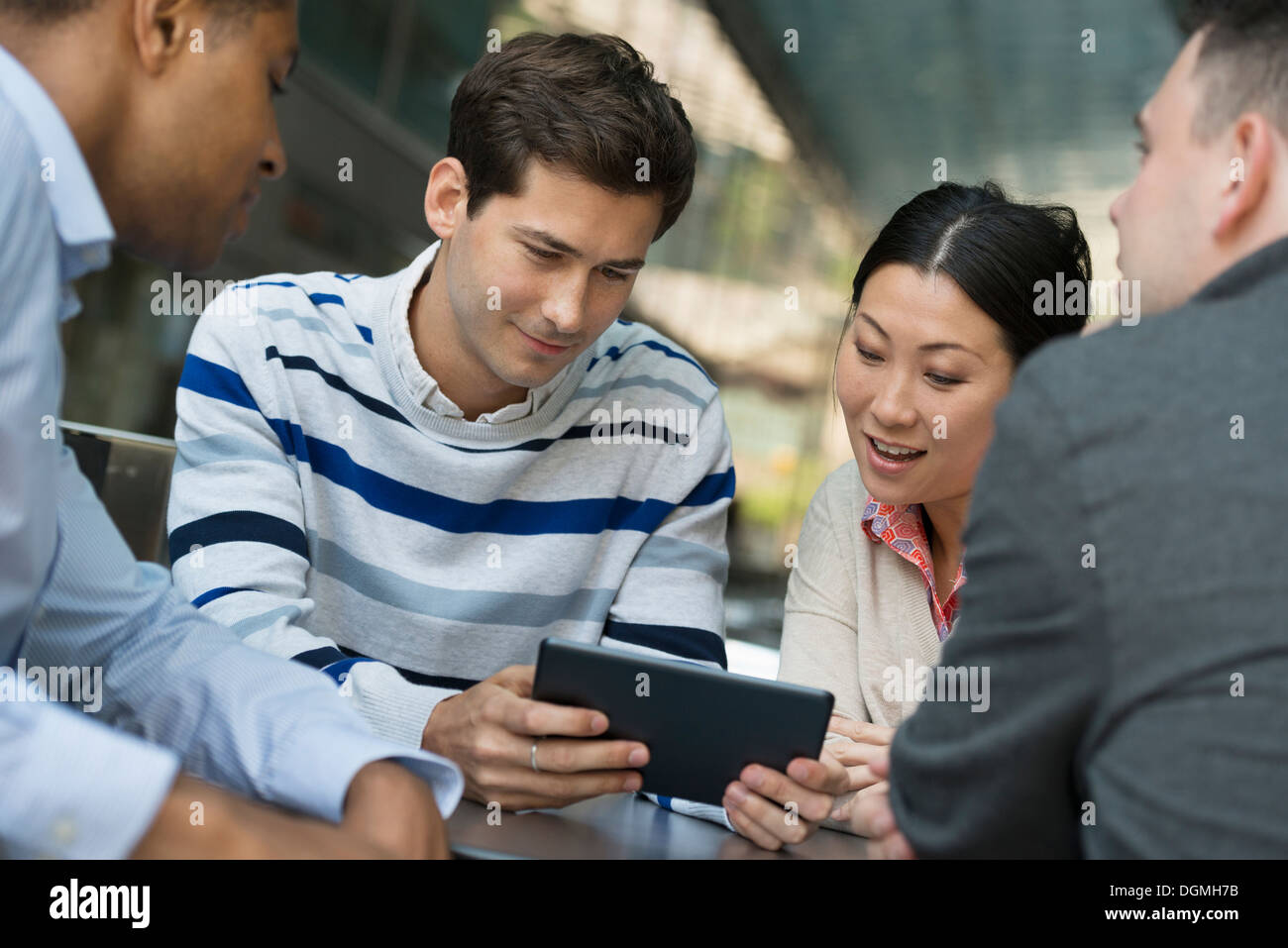 Geschäftsleute unterwegs. Vier Menschen versammelten sich um ein digital-Tablette eine Diskussion. Stockfoto