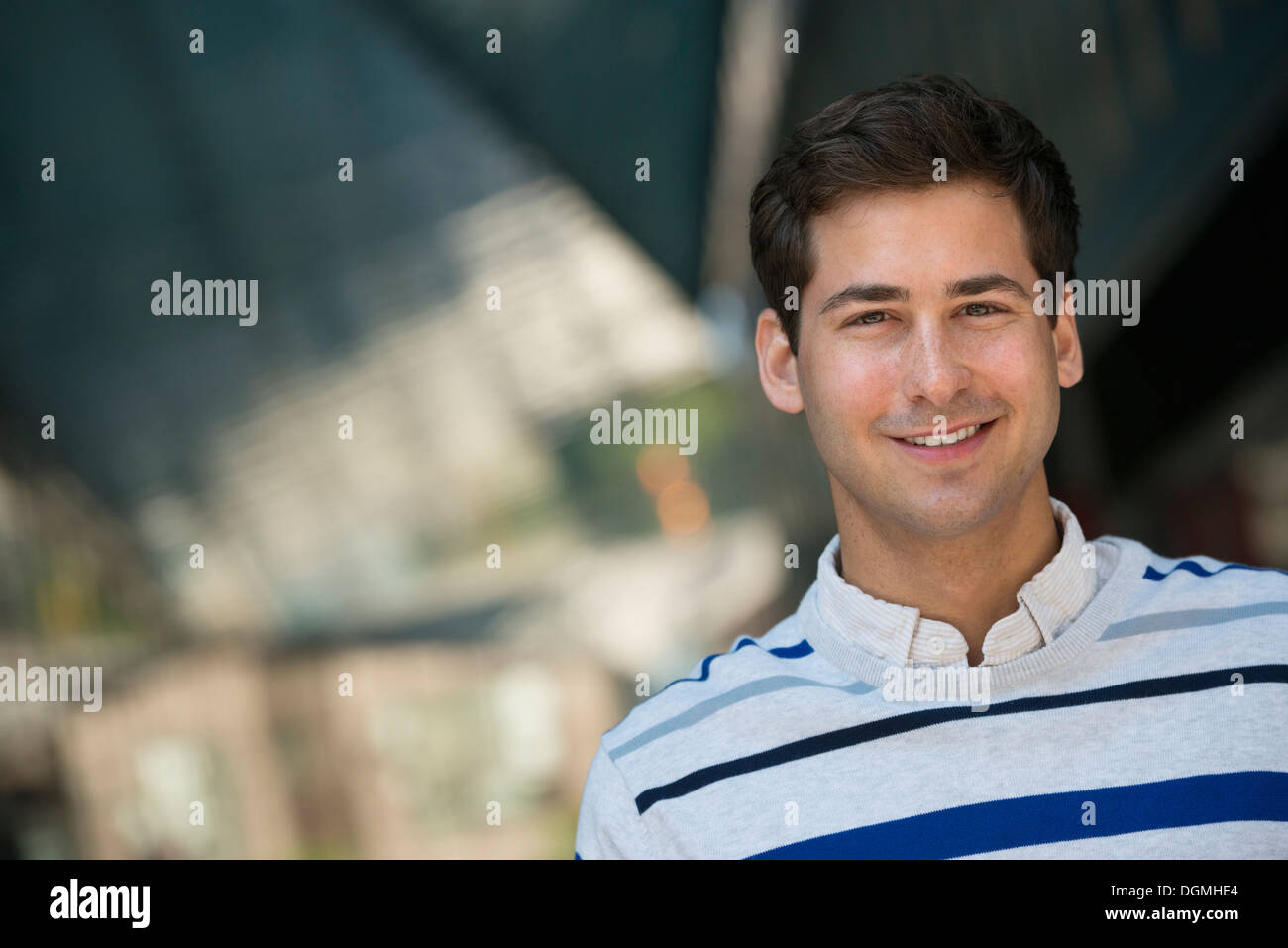 Geschäftsleute unterwegs. Ein junger Mann in einem gestreiften Pullover in die Kamera schaut. Stockfoto