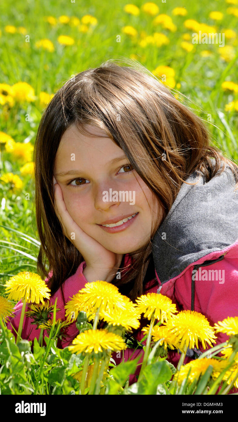 Mädchen, 12 Jahre, liegend in einem Feld von Löwenzahn, Lächeln Stockfoto