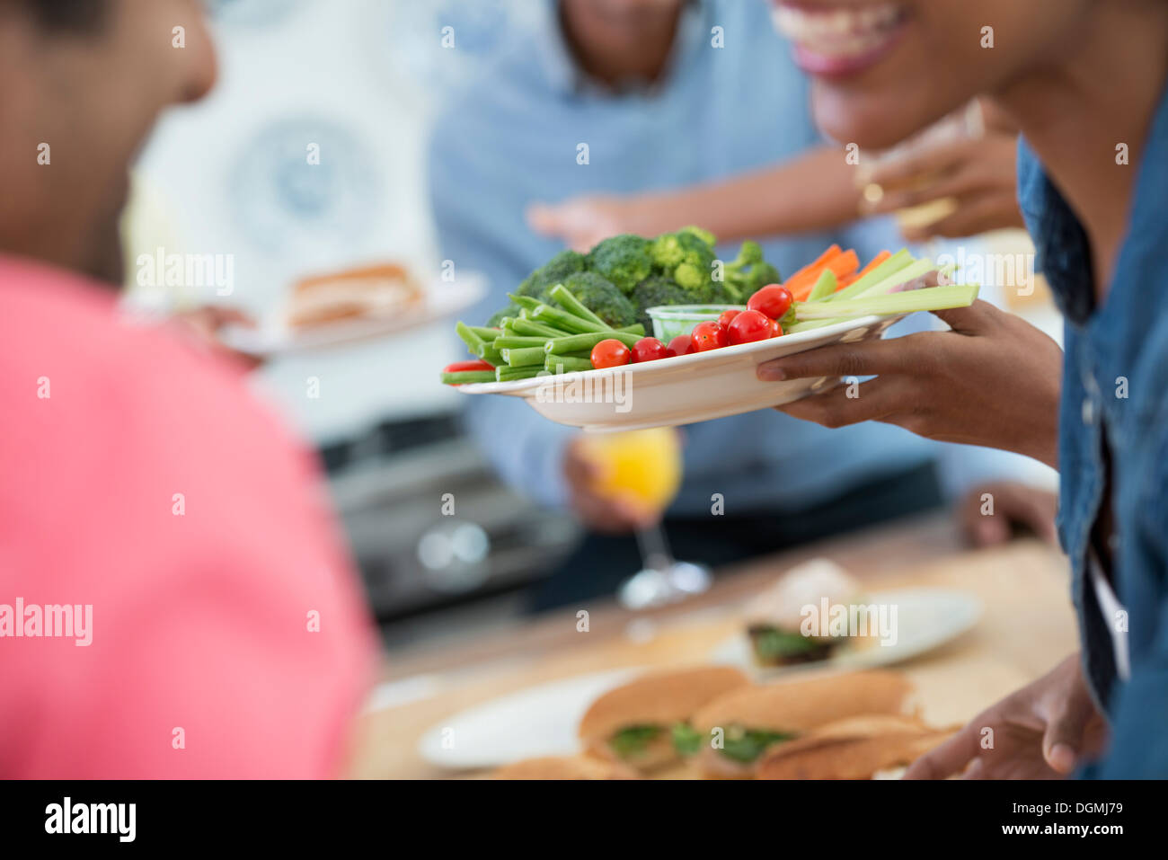 Ein informelles Büro-Ereignis. Menschen, die Ausgabe von Platten von Lebensmitteln über ein Buffet-Tisch. Stockfoto