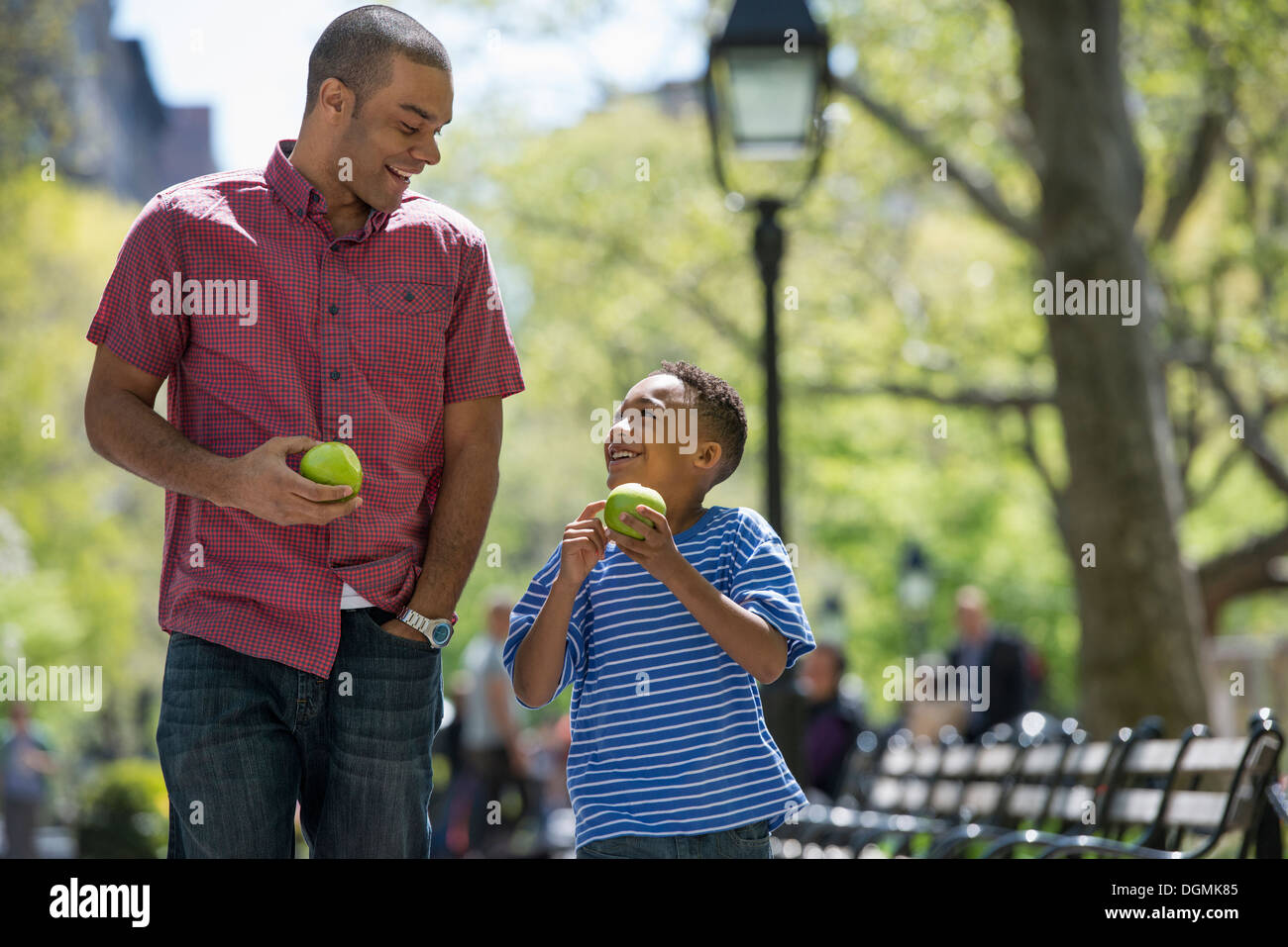 Eine Familie im Park an einem sonnigen Tag. Ein Mann und eine junge Verzehr von Äpfeln. Stockfoto