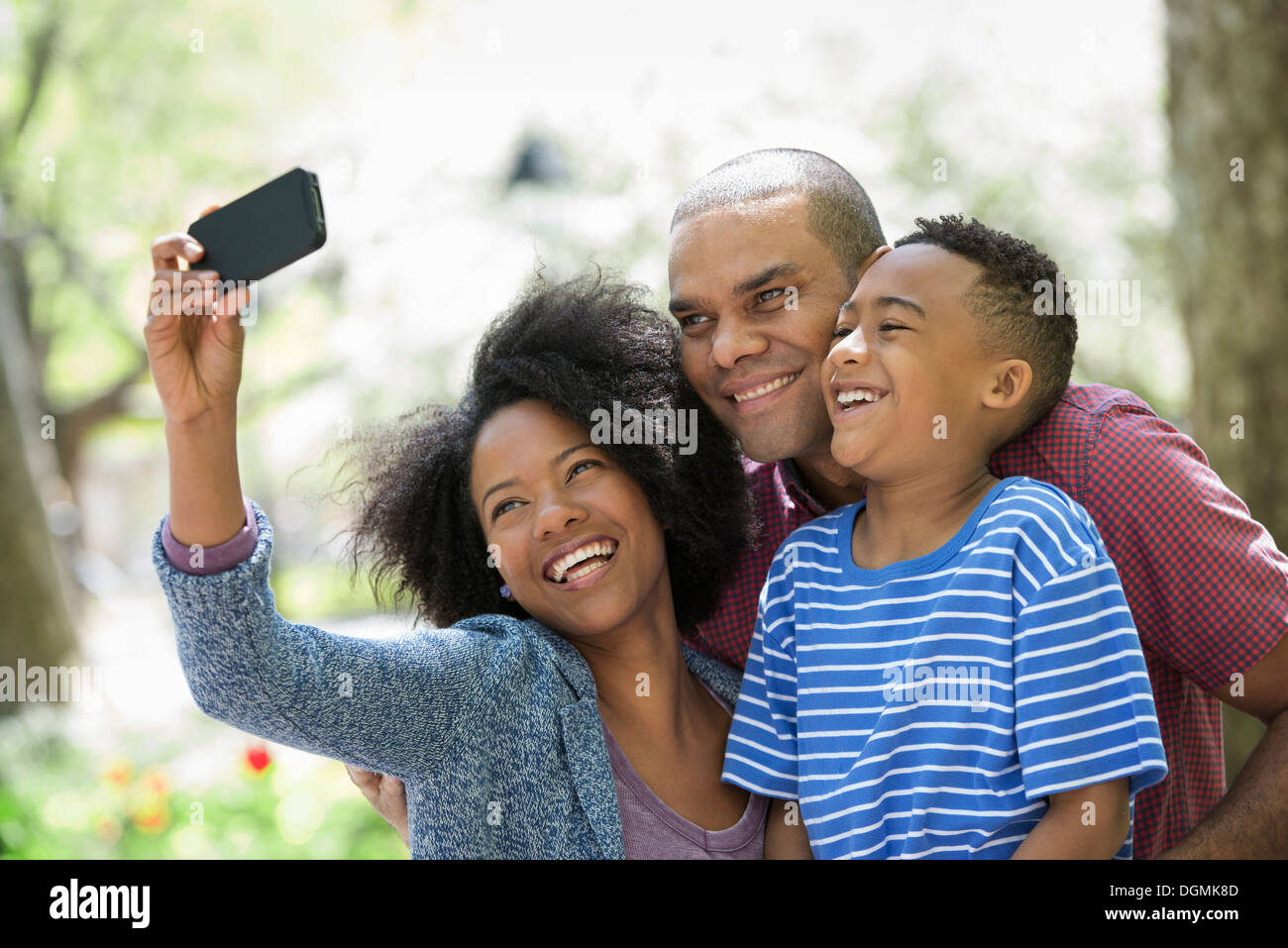 Zwei Erwachsene und ein kleiner Junge mit einem Smartphone zu fotografieren. Stockfoto