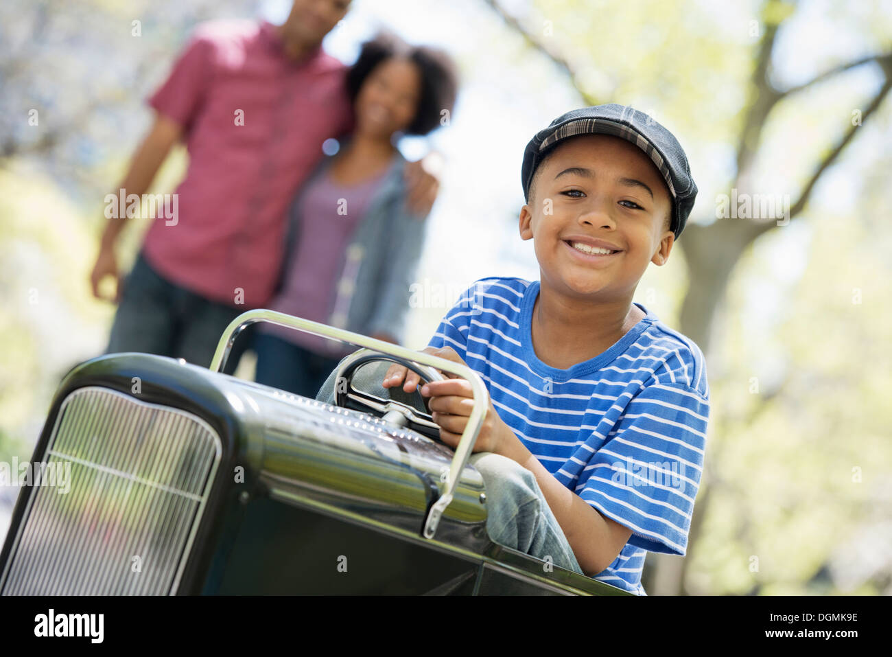 Ein Junge Reiten eine altmodische Spielzeug hausieren Auto. Stockfoto