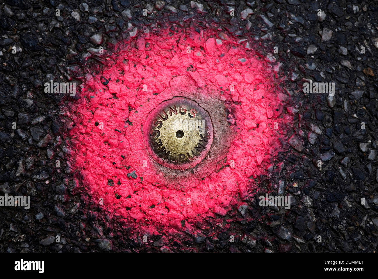 Eine feste Messstelle für Vermesser, in die Fahrbahn eingelassen und mit rosa Sprühfarbe markiert Stockfoto