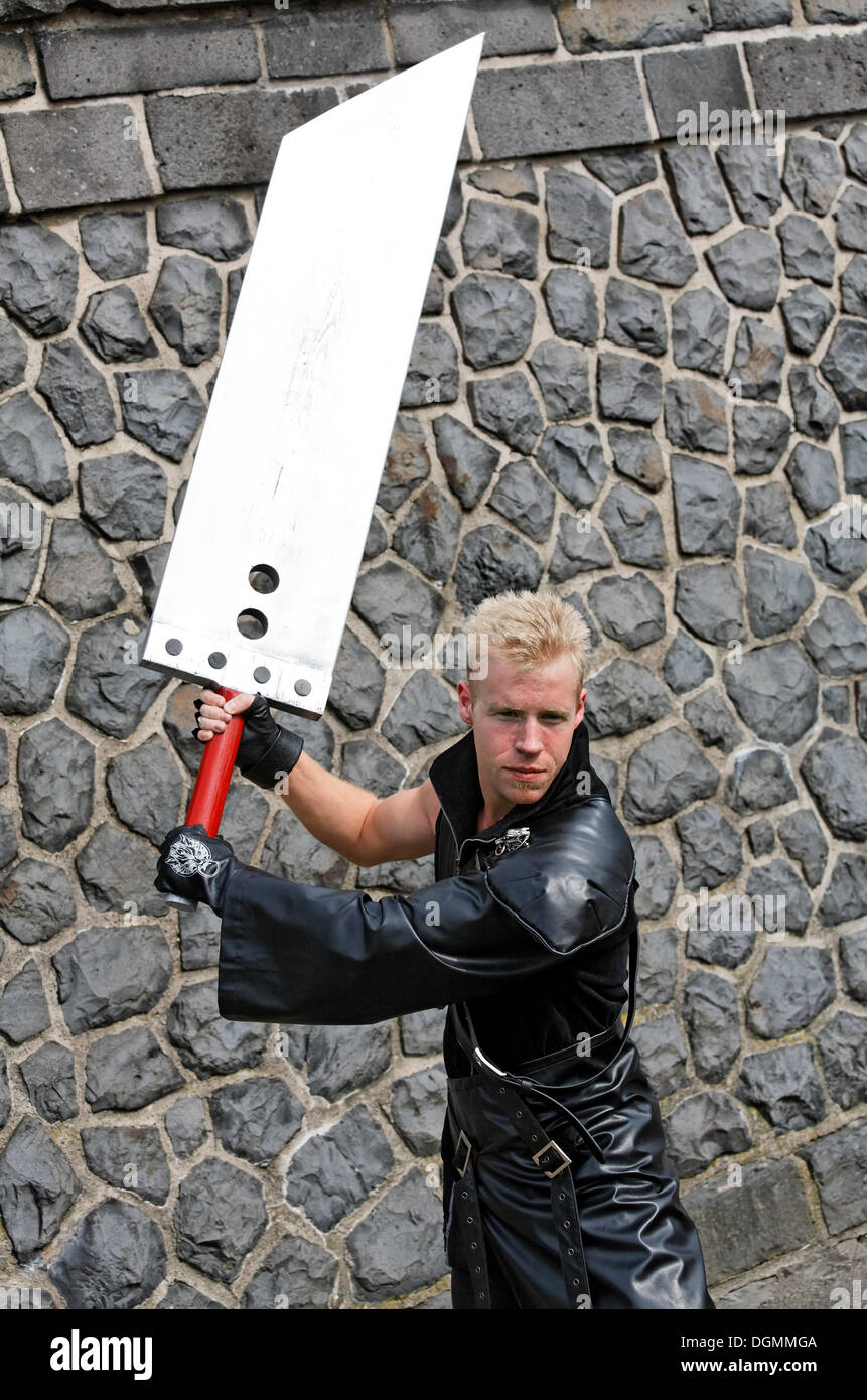 Junger Mann in Leder schwingen Riesen Messer, kostümiert wie eine japanische Anime-Charakter oder Manga-Charakter, cosplayer Stockfoto