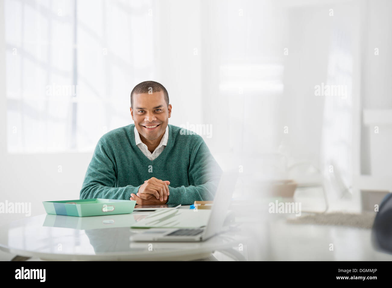 Geschäft. Ein Mann sitzt mit gefalteten Händen hinter einem Schreibtisch. Stockfoto