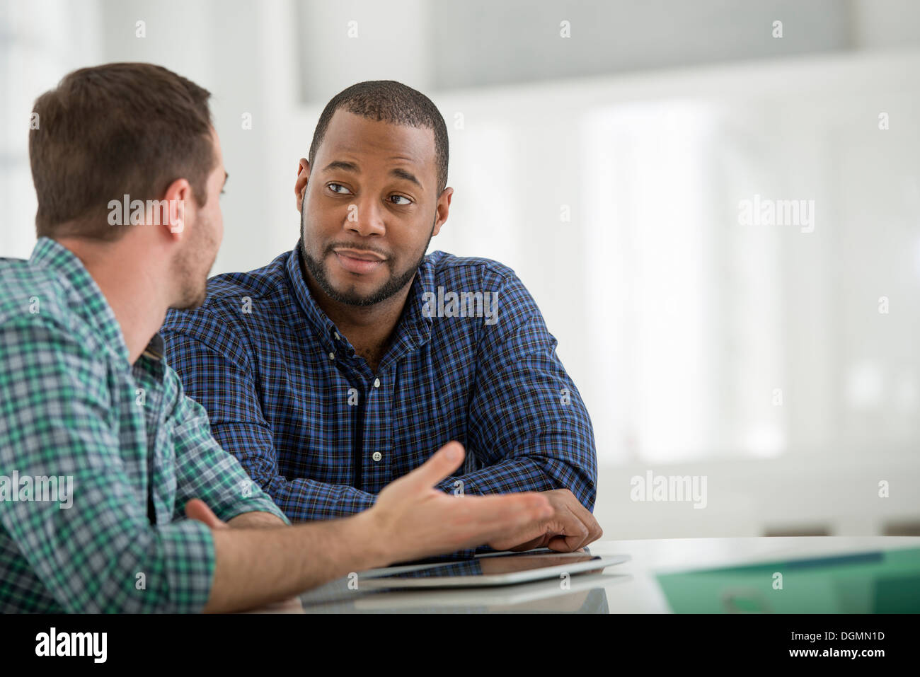 Büroeinrichtung. Zwei Männer an einem Tisch sitzen und mit einem digital-Tablette. Stockfoto