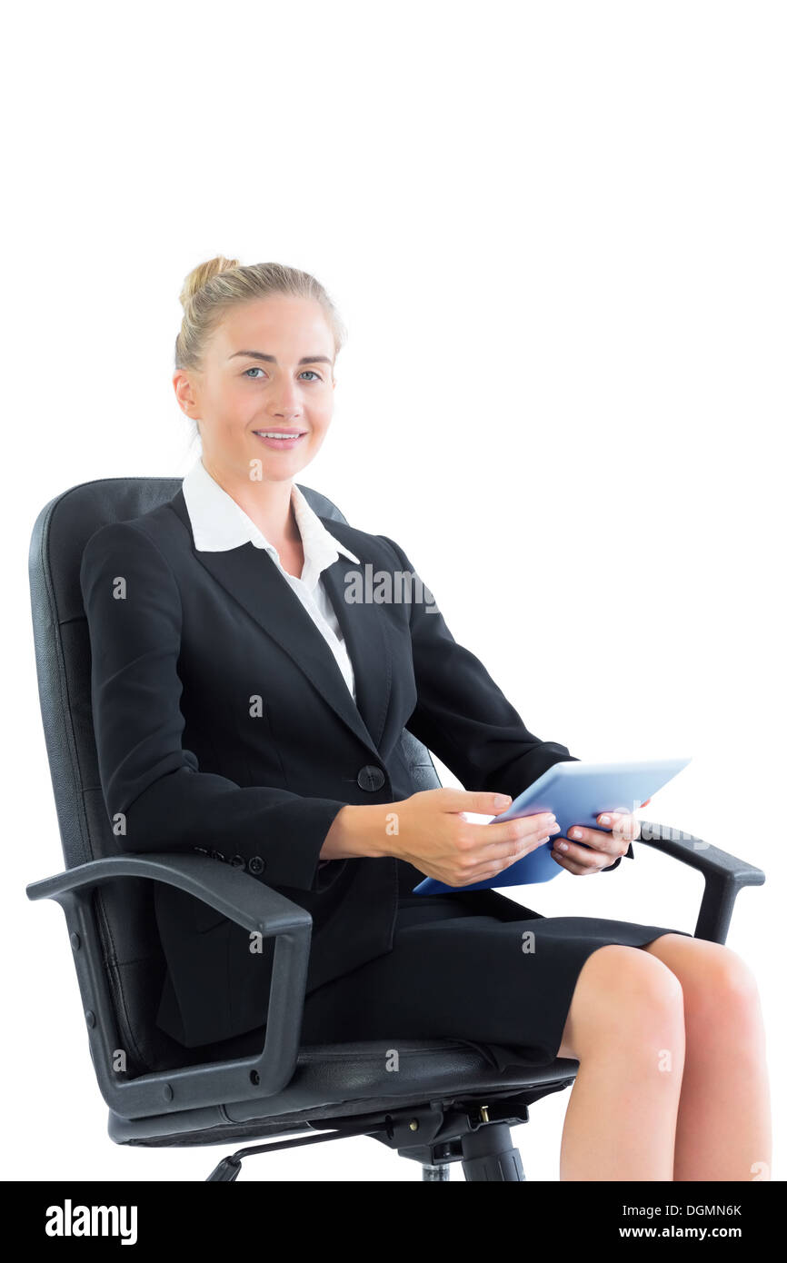 Attraktive gut gekleidet Geschäftsfrau sitzen auf einem Bürostuhl hält eine Tablette Stockfoto