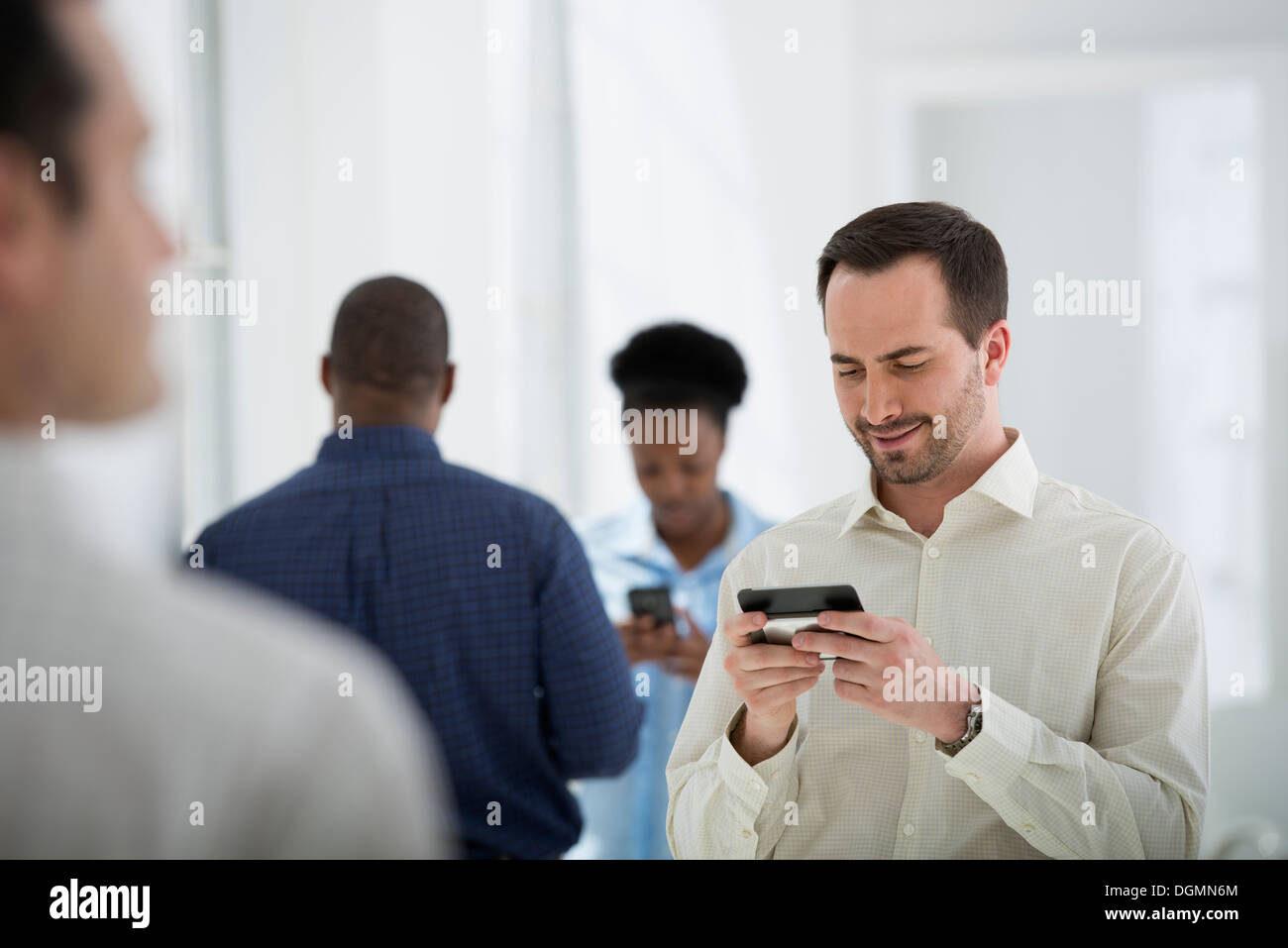 Büroeinrichtung. Eine Gruppe von Menschen, ein Mann mit einem Smartphone. Stockfoto