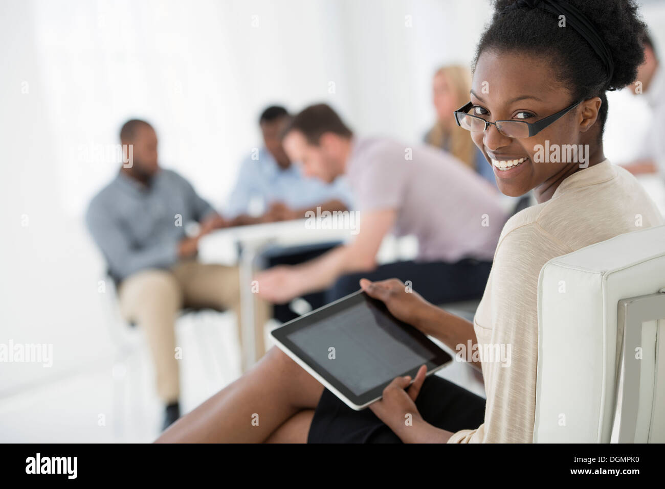 Büroeinrichtung. Treffen. Eine Person, die auf der Suche über die Schulter und von der Gruppe entfernt. Halten eine digitale-Tablette. Stockfoto