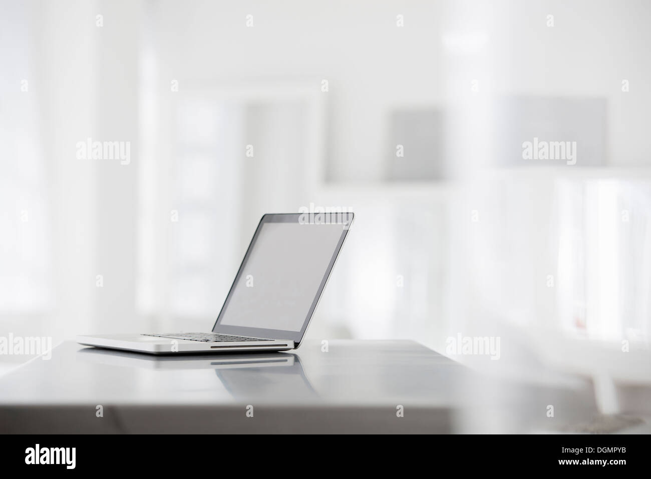 Büroeinrichtung. Eine glatte glänzende graue Tischplatte und einer offenen Laptop-Computer. Stockfoto