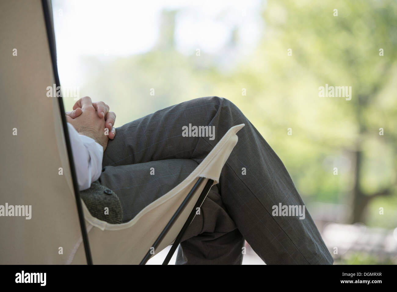 Leben in der Stadt. Ein Mann sitzt in einer Leinwand Campingstuhl im Park. Stockfoto