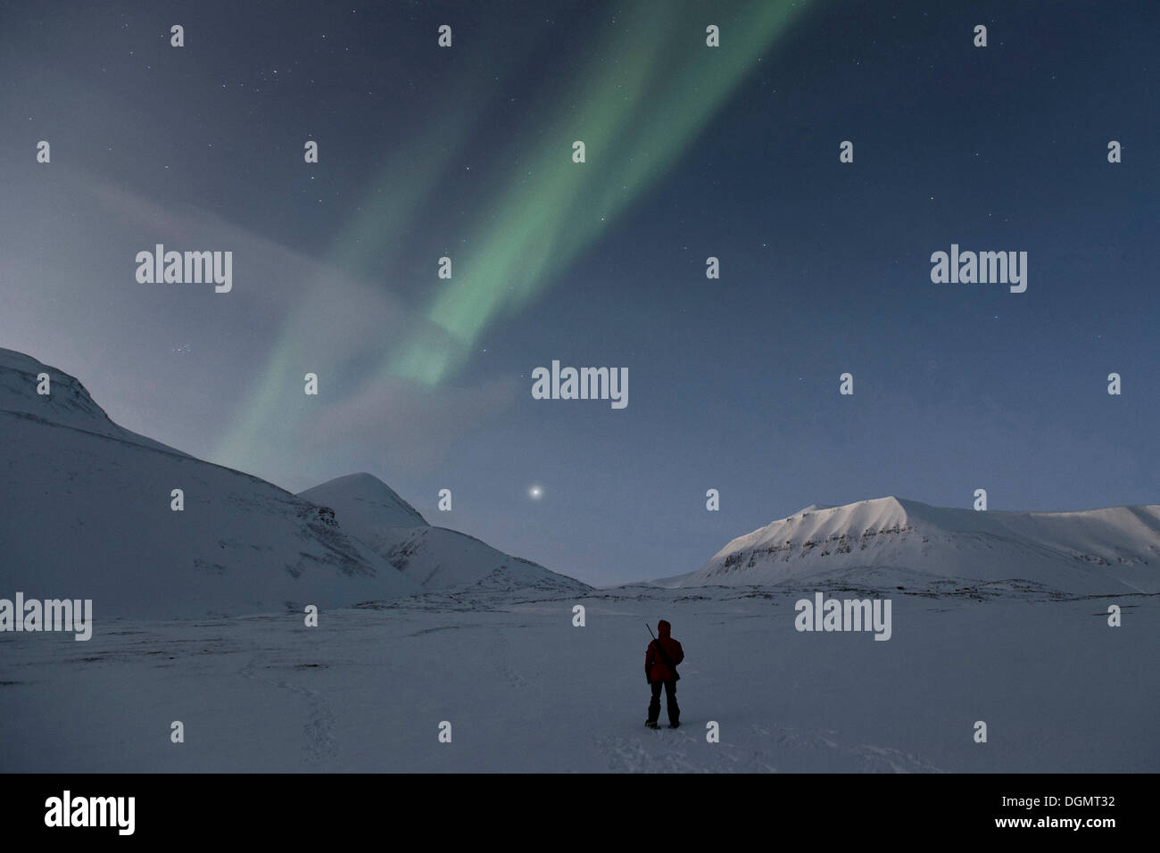 Person, die eine Gewehr ist das Nordlicht und der Sternenhimmel, Spitzbergen, Svalbard, Norwegen, Europa bewundern. Stockfoto