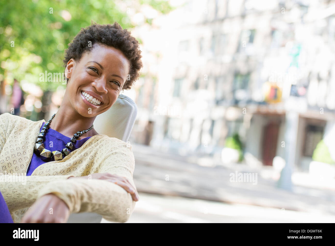 Leben in der Stadt. Eine Frau sitzt an der frischen Luft in einem Stadtpark. Stockfoto