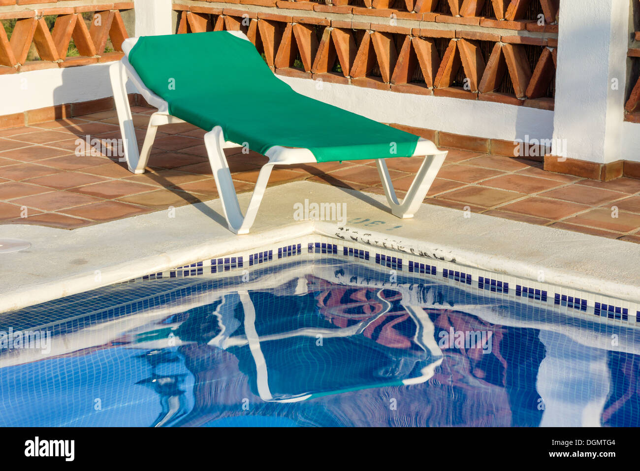 Eine Sonnenliege sitzt neben dem einladenden Wasser eines spanischen Swimmingpools. Stockfoto