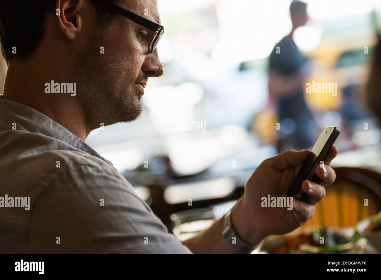 Geschäft unterwegs. Ein Mann sitzt in einem Cafétisch, mit seinem Handy. Blick nach unten auf dem Bildschirm. Stockfoto