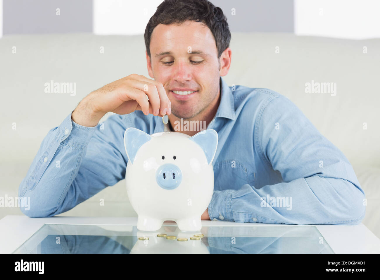 Inhalt legerer Mann, Münze in Sparschwein Stockfoto