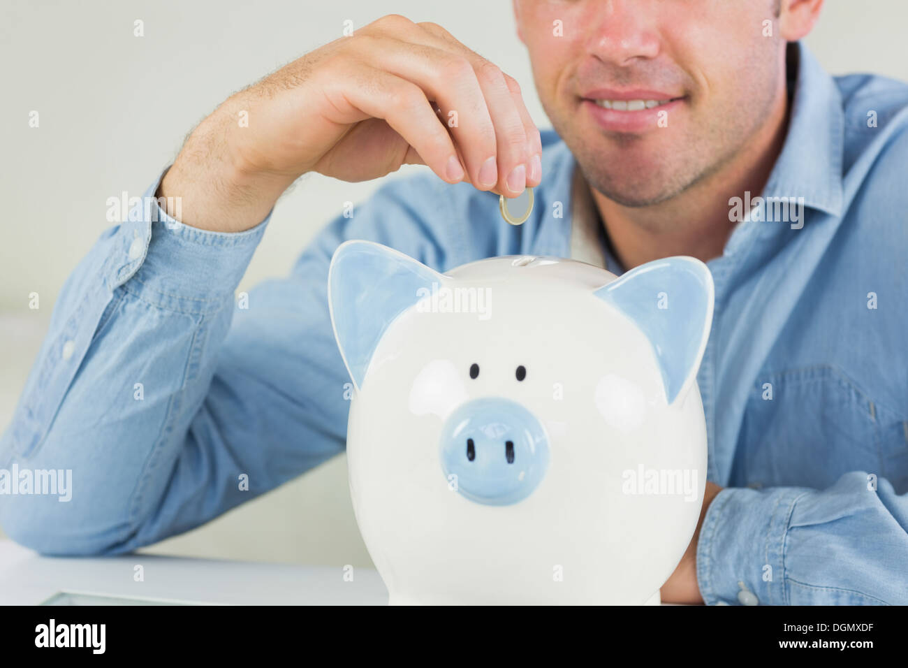 Glücklich legerer Mann, Münze in Sparschwein Stockfoto