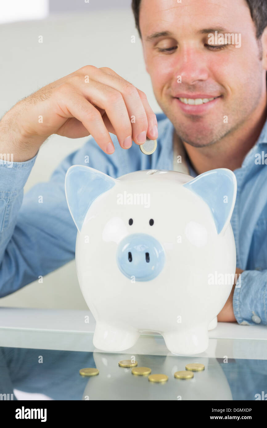 Legerer Mann, Münze in Sparschwein lachen Stockfoto