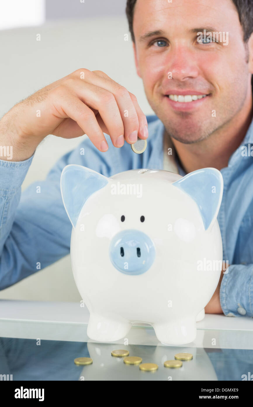 Attraktive legerer Mann, Münze in Sparschwein Stockfoto