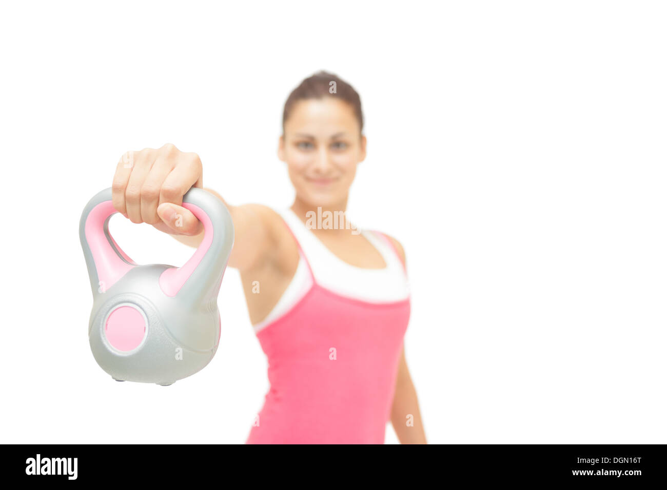 Lächelnde getönten Brünette zeigt graue und rosa kettlebell Stockfoto