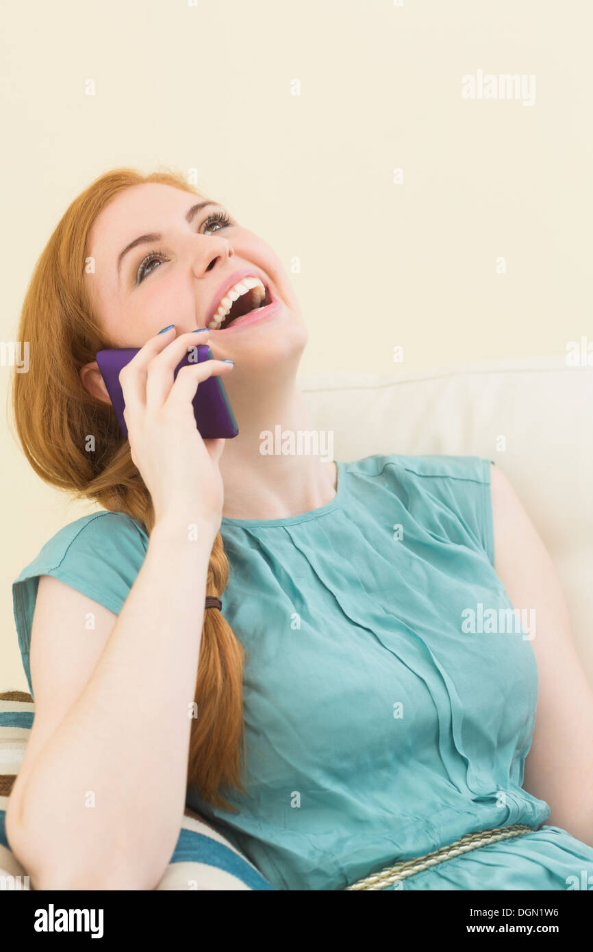 Lachende Rothaarige sitzen auf der Couch einen Anruf tätigen Stockfoto