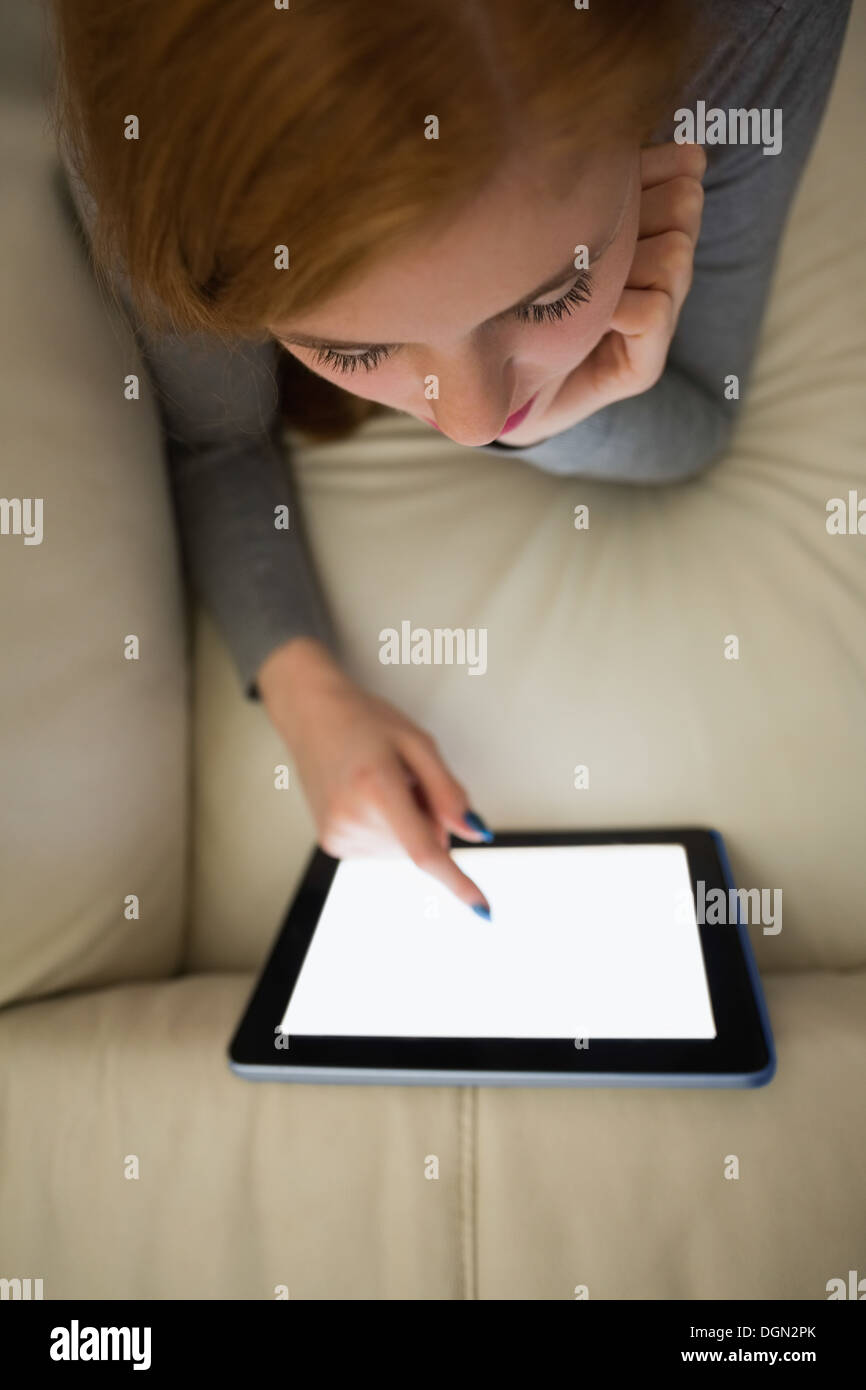 Rothaarige auf der Couch mit ihrem Tablet-pc Stockfoto