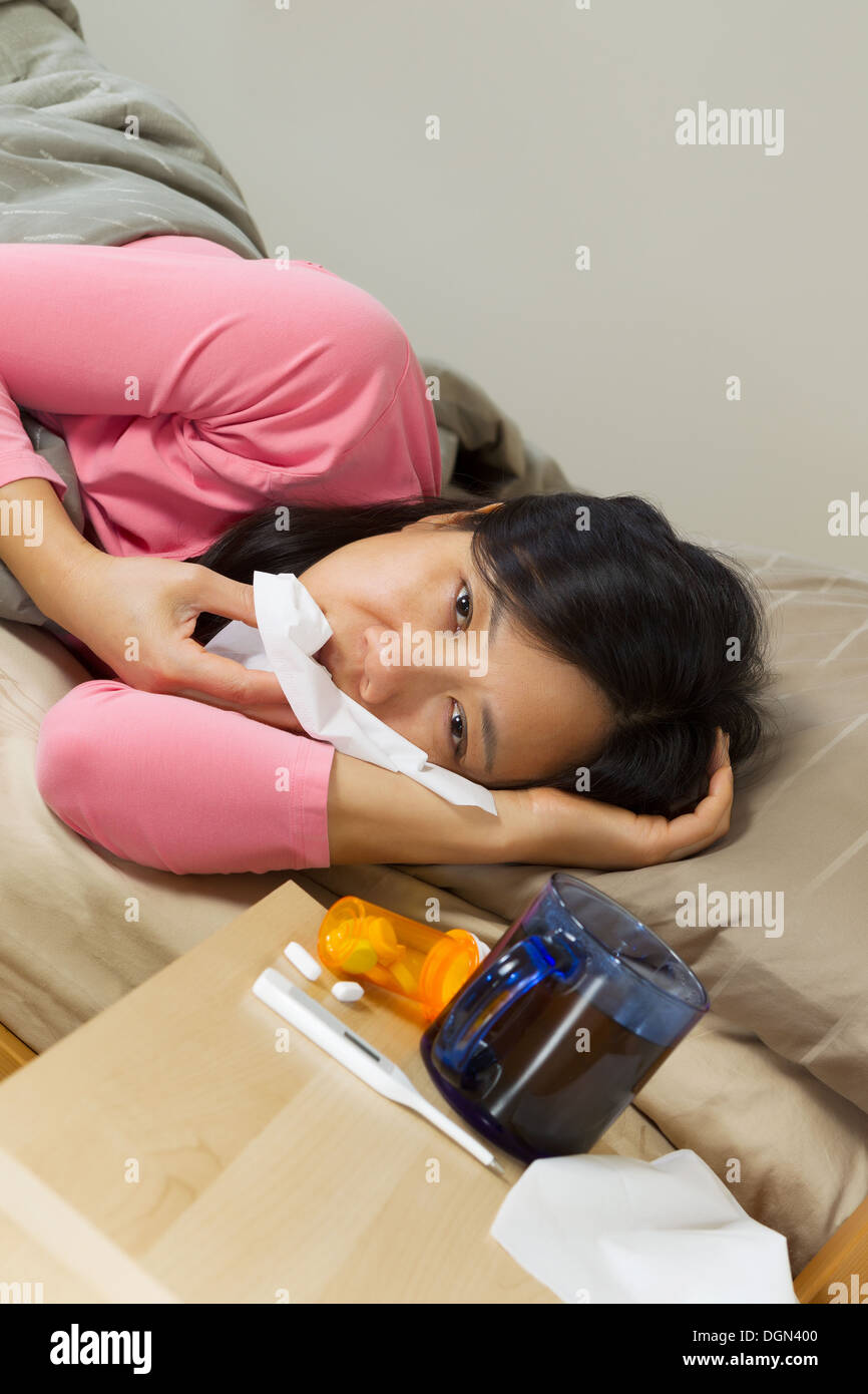 Vertikale Foto Reife Frau ihre Nase mit einem Taschentuch abwischen, krank im Bett liegend Stockfoto