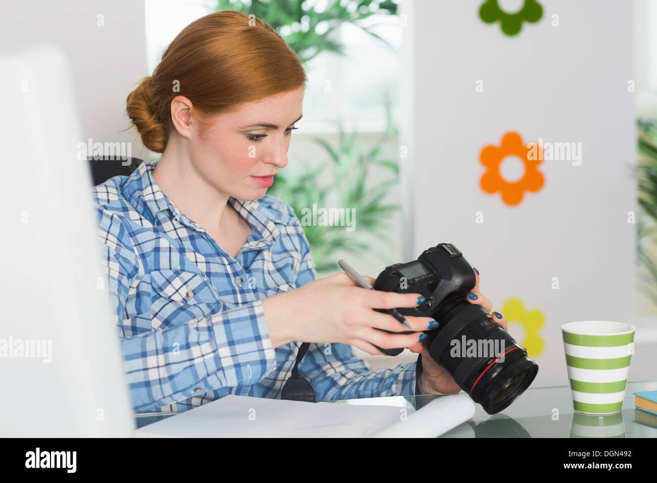 Konzentrierte sich Fotograf sitzt an ihrem Schreibtisch in ihrer Kamera schaut Stockfoto