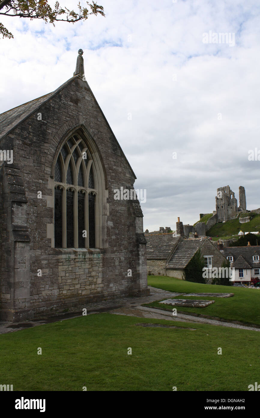 Westwand der Corfe Castle Pfarrkirche, St. Edward der Märtyrer, mit der Burg im Hintergrund. Stockfoto