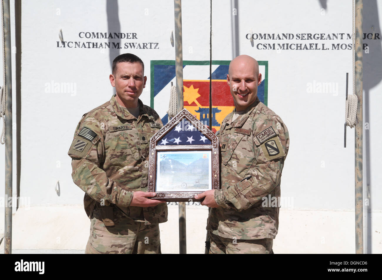 US Air Force Captain Jared King (rechts), erhält ein Forrest Hill, MD., Native / Cyber-Kriegsführung-Operator an Central Command Materiel Recovery Element befestigt, eine Flagge und ein Zertifikat vom US Army Lieutenant Colonel Nathan Swartz, ein Eingeborener von Tullahoma, Tennessee, eine Stockfoto