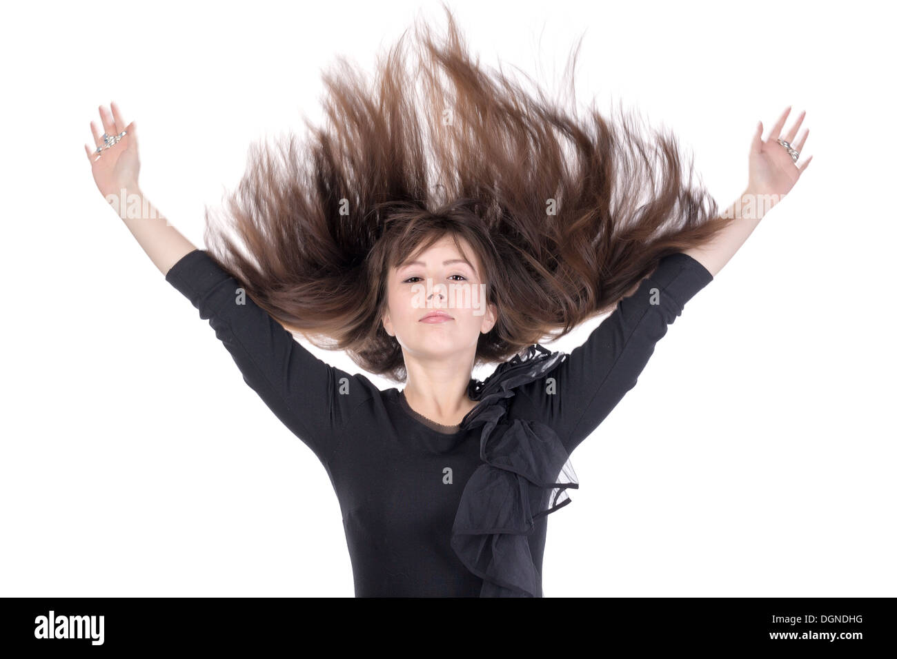Junge Frau mit ihrem lange gerade brünette Haare fliegen in der Luft und ihre Arme über den Kopf, isoliert auf weiss Stockfoto
