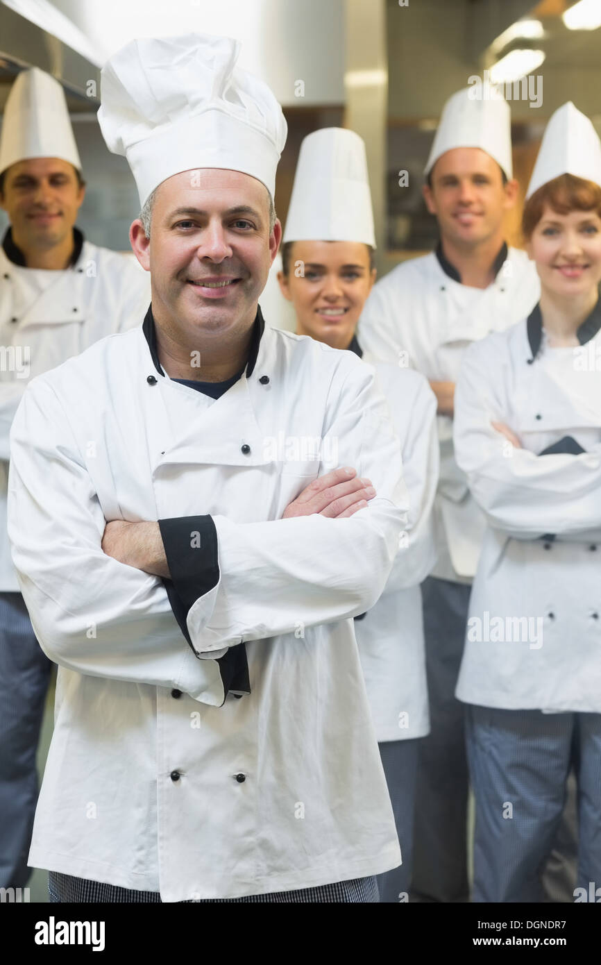 Fünf Köche tragen Uniformen beim Posieren in einer Küche Stockfoto