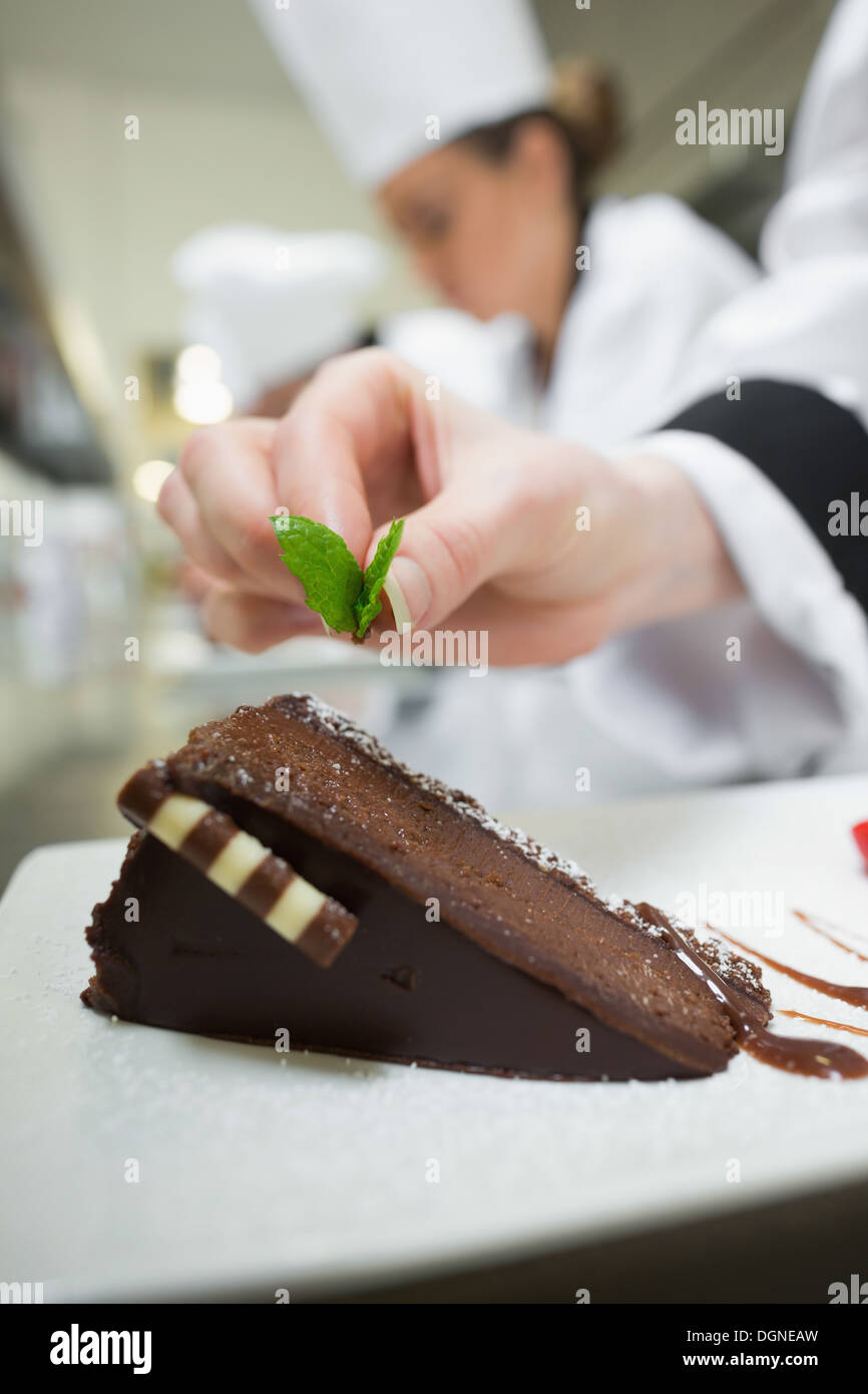 Nahaufnahme von Küchenchef Schokoladendessert Minzblatt aufsetzen Stockfoto