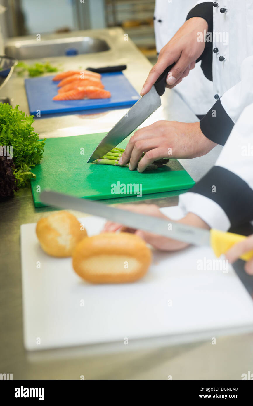 Nahaufnahme der Köche schneiden Brötchen und Spargel Stockfoto