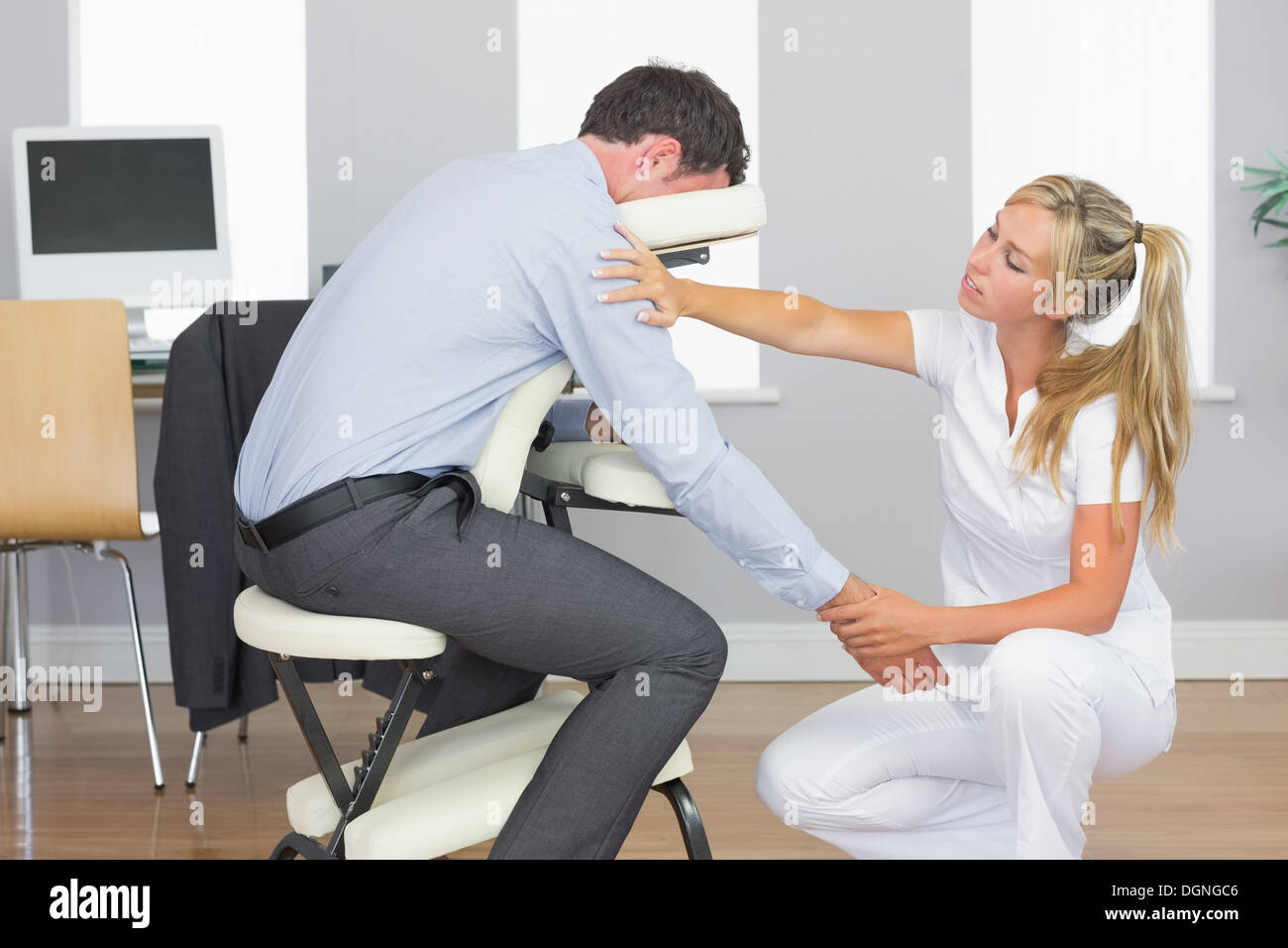 Masseurin, die Behandlung von Kunden Arm bei Massage-Sessel Stockfoto