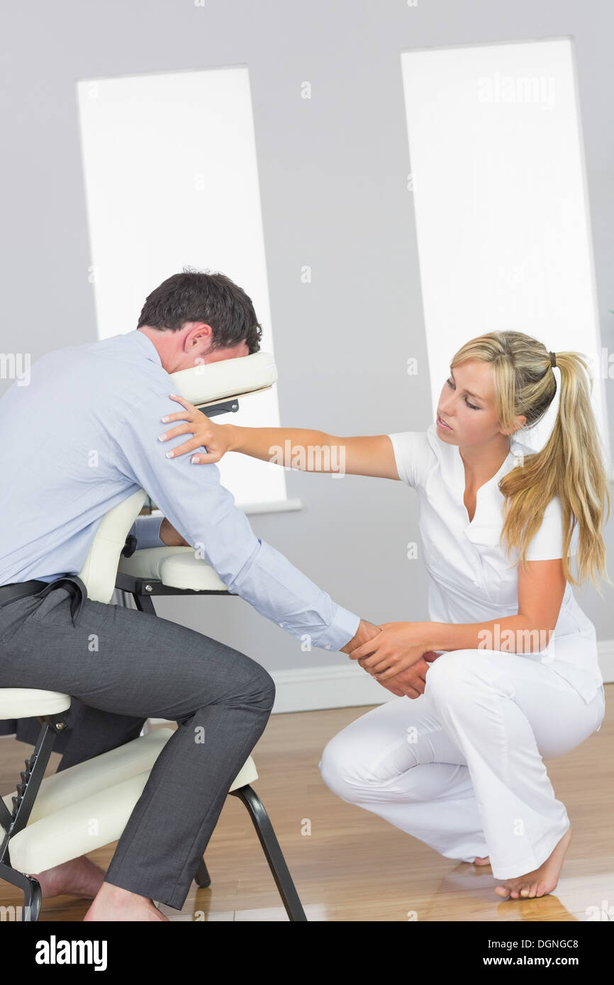 Masseurin massiert Kunden Arm in Massage-Stuhl Stockfoto