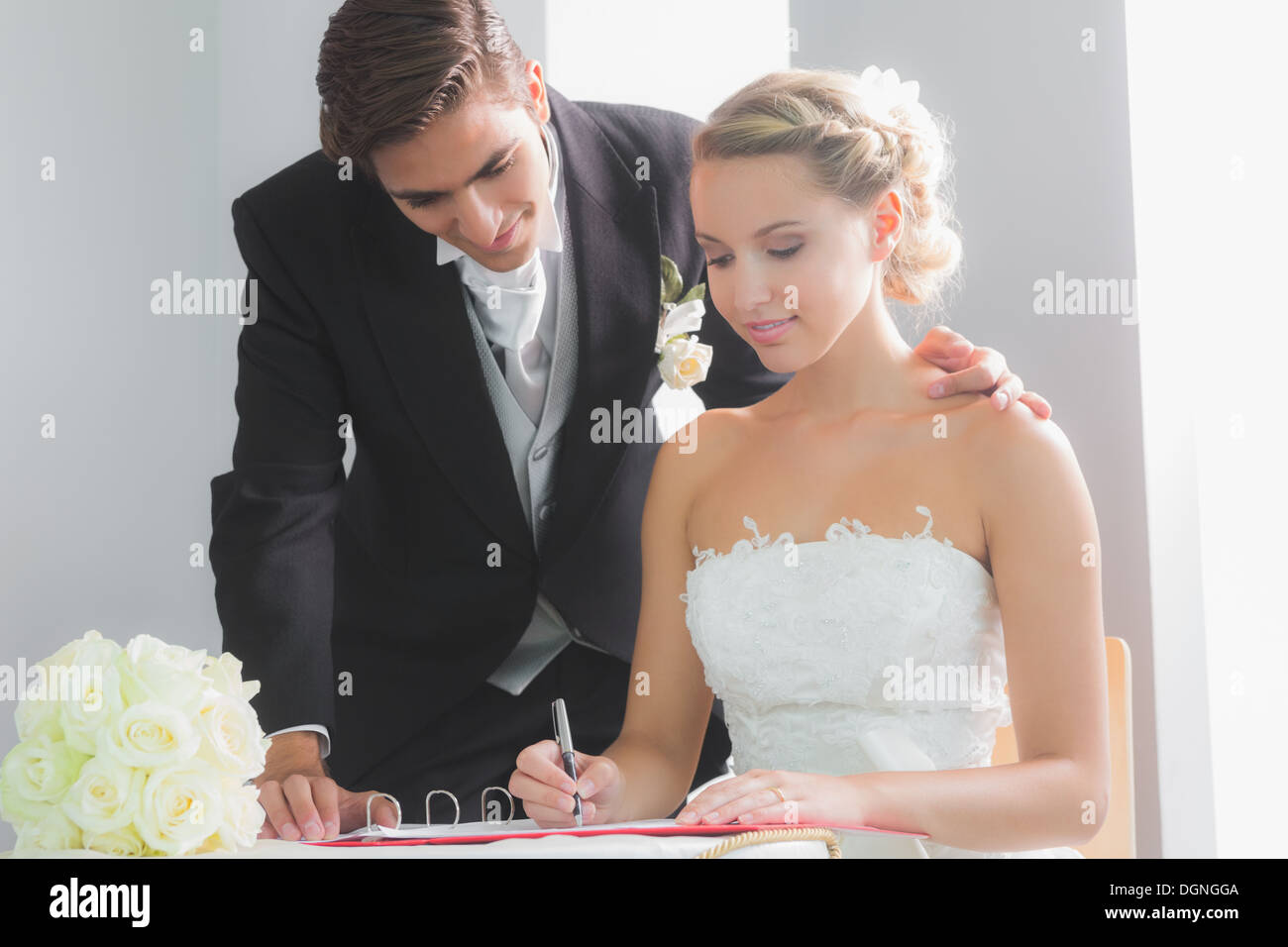 Junge blonde Braut sitzt am Tisch, die Unterzeichnung Hochzeit register Stockfoto