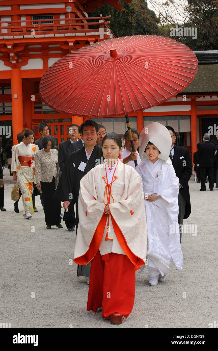 Japanische Frau mit scharlachroten Hakama Hosen und einem weißen Kimono Shirt mit langen Ärmeln, vor dem Torhaus von Stockfoto