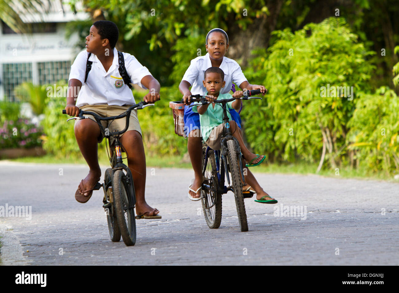 Kinder tragen Schuluniformen beim Radfahren, La Digue Island, Seychellen, Afrika, Indischer Ozean Stockfoto