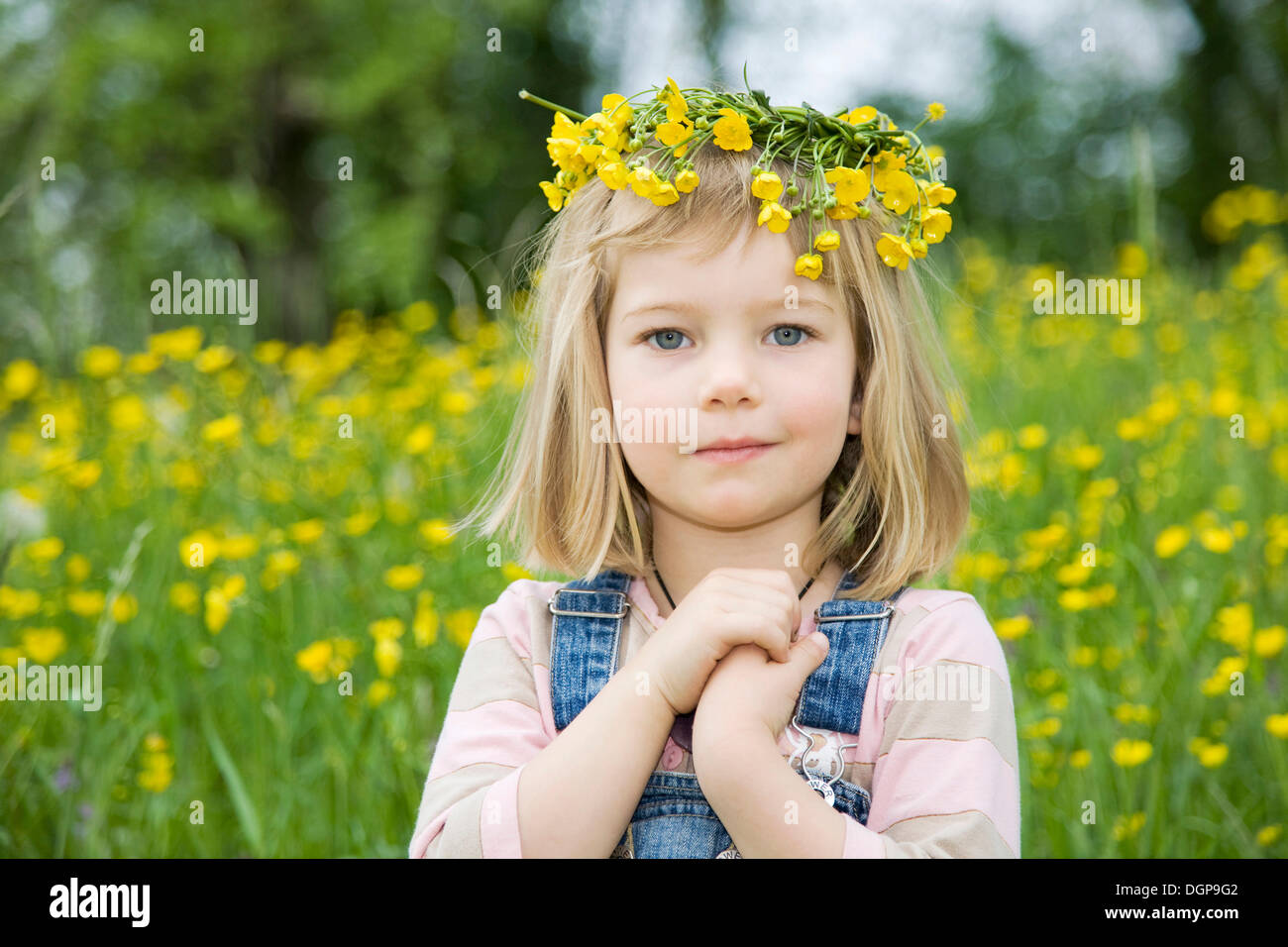 Mädchen tragen einen Blumenkranz auf dem Kopf, sitzt auf einer Blumenwiese, Porträt Stockfotografie