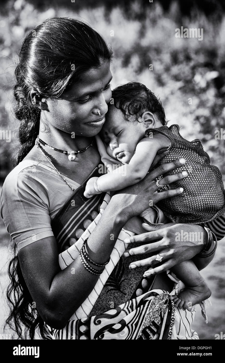Glücklich niedrigere Kaste Indianerin wiegt ihr schlafendes Baby. Andhra Pradesh, Indien. Monochrom Stockfoto