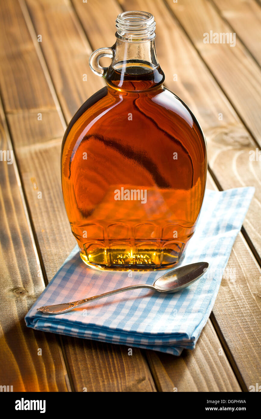 Ahornsirup in Glasflasche auf Holztisch Stockfoto