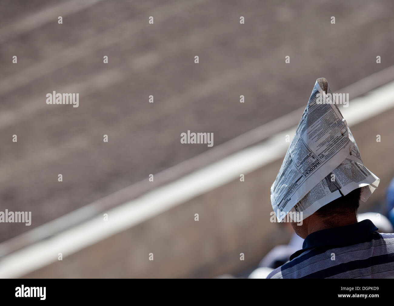 Mann mit einer Zeitung als eine improvisierte Hut zum Schutz vor der Sonne während des Spiels Pferd am Nationalfeiertag, Bischkek, Kirgisistan Stockfoto