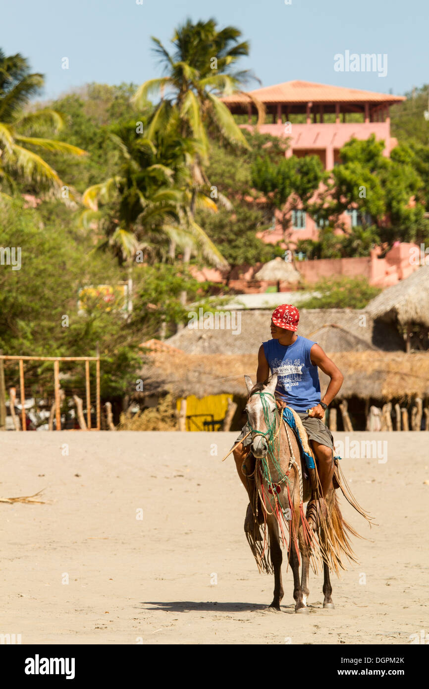 Ein Mann auf einem Pferd am Strand von La Boquita, Nicaragua. Stockfoto Ein Mann auf einem Pferd am Strand von La Boquita, Nicaragua. Stockfoto
