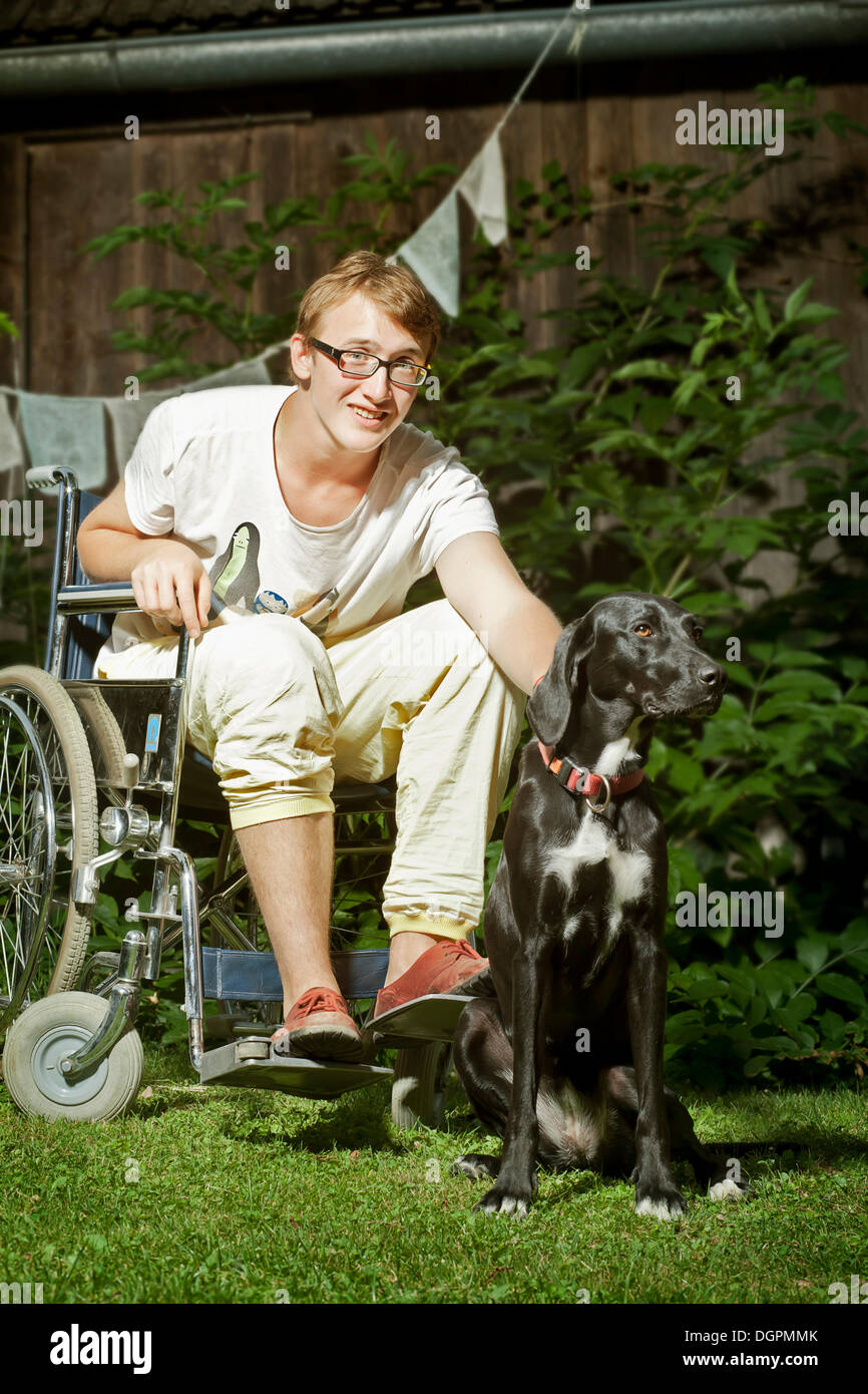 Teenager sitzen im Rollstuhl, mit Begleithund, Therapiehund Stockfoto