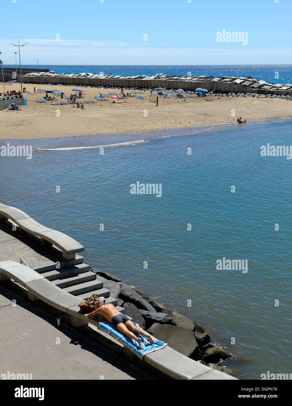 Madeira Portugal. Ein Mann Sonnenbaden Verlegung mit dem künstlichen Calheta Strand im Hintergrund verdeckt Stockfoto
