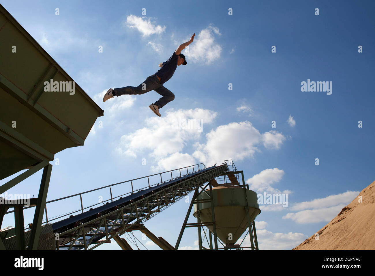 Junger Mann springt aus einem Förderband in einem Sandkasten, Oettingen in Bayern Stockfoto