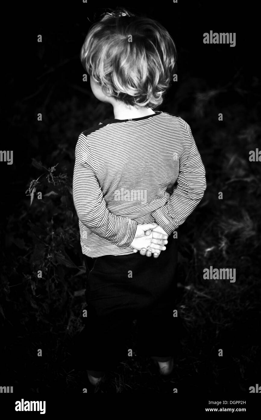Kleiner Junge stehend mit den Händen hinter seinem Rücken verschränkt Stockfoto