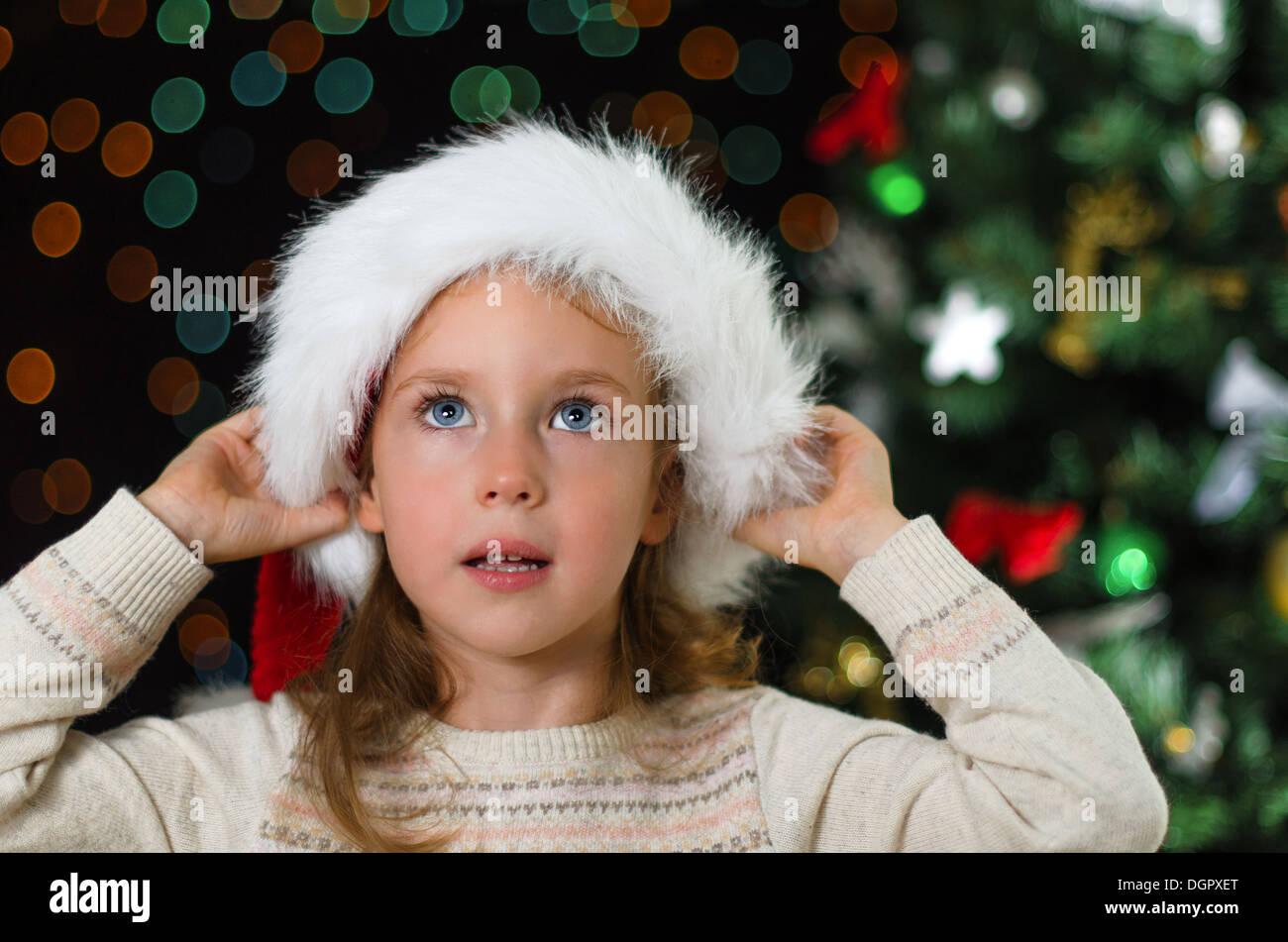 Kleines Mädchen in Nikolausmütze über Weihnachtsbaum Stockfoto